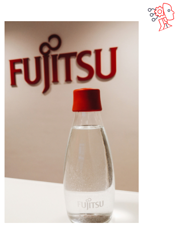 Fujitsu-branded glass bottle with water placed in front of the red Fujitsu logo, symbolizing commitment to sustainability